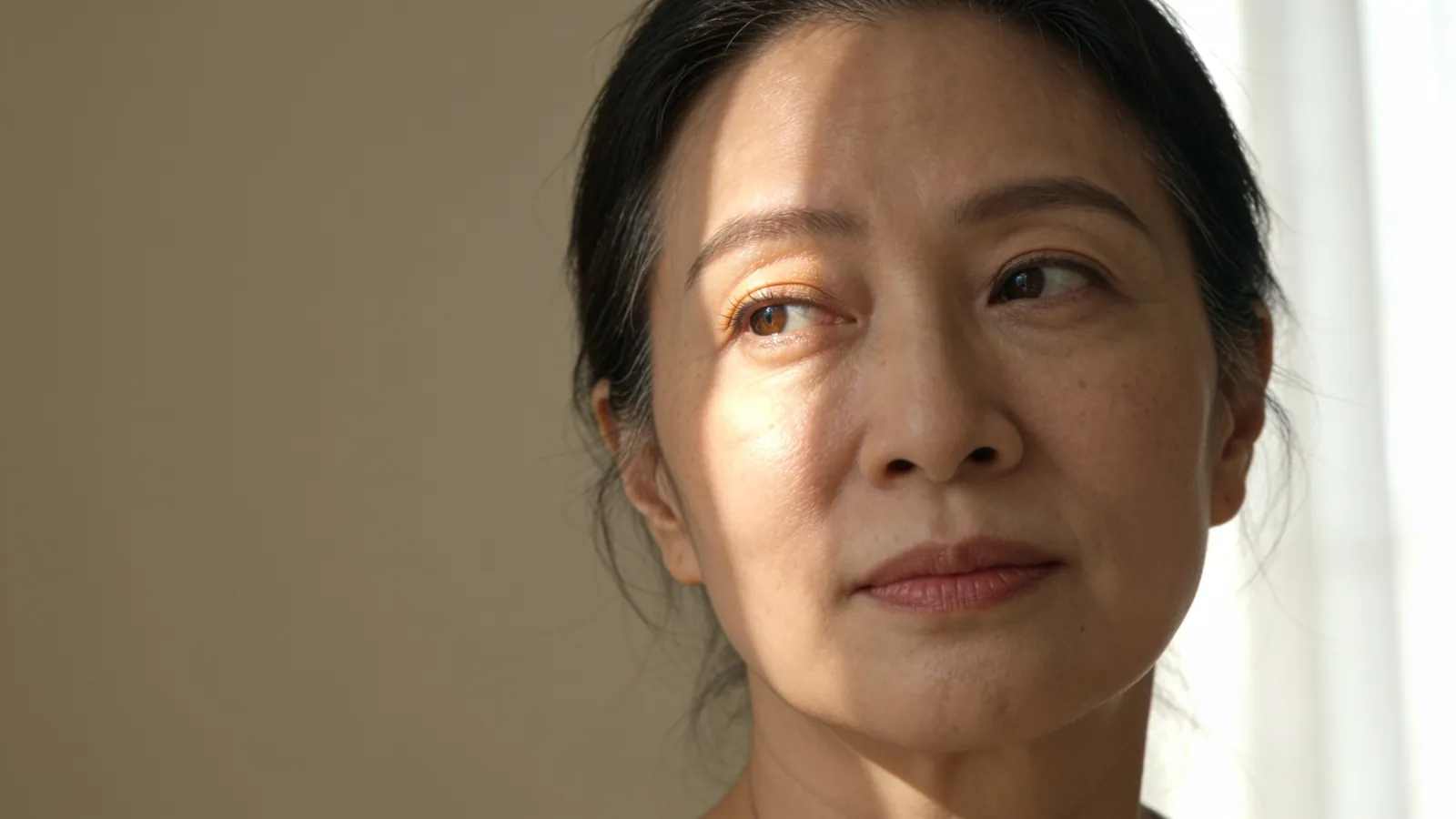 Woman in her forties in soft window light, under-eye area in focus