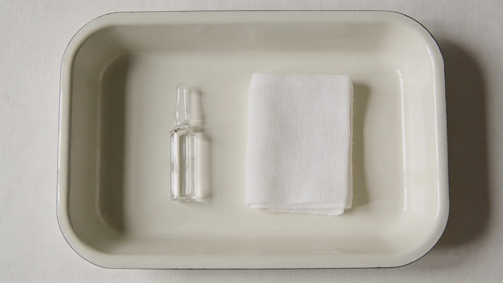 Empty glass vial and gauze on a pale tray