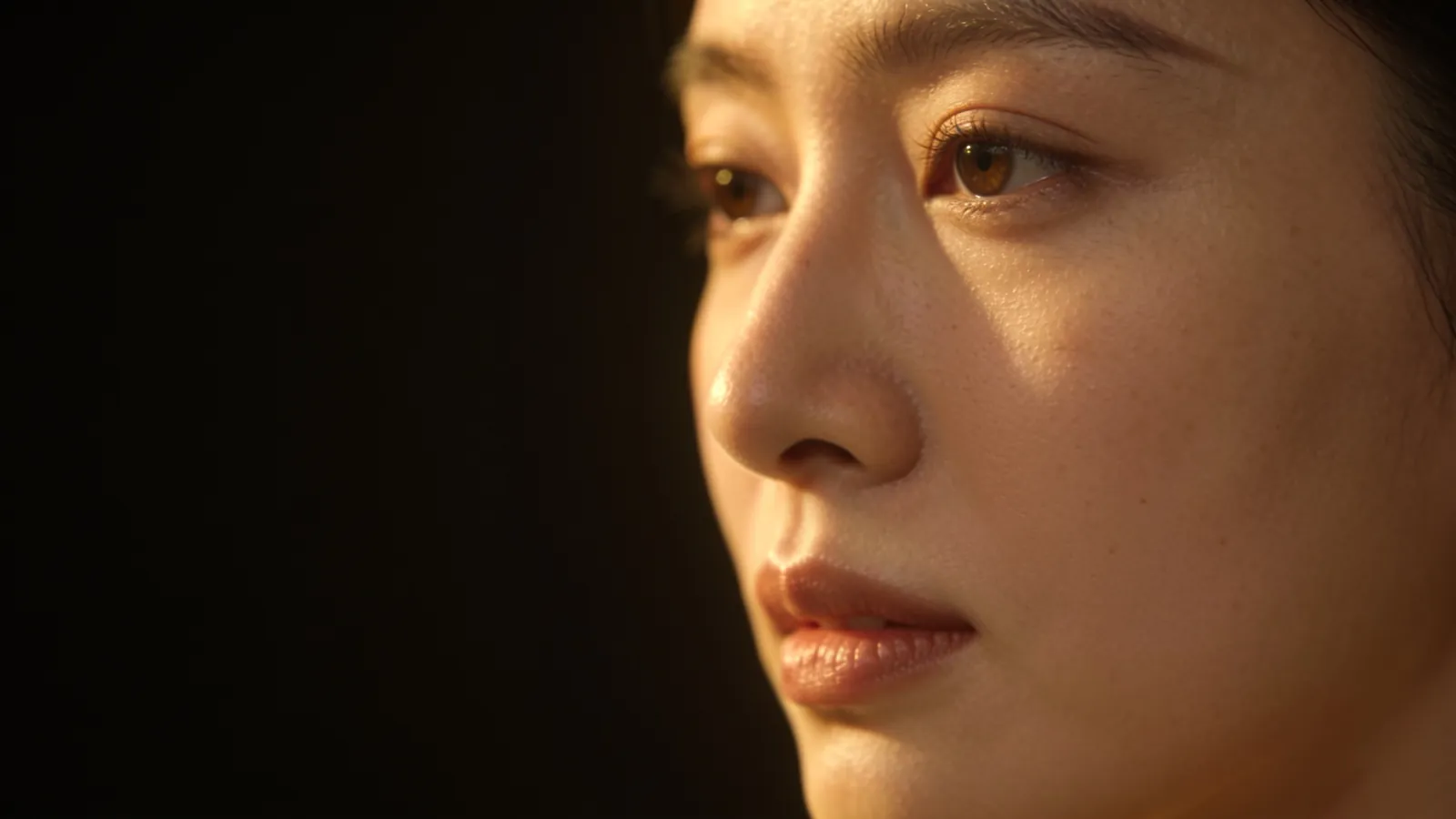 Close-up of a woman's face with smooth, even skin in warm light