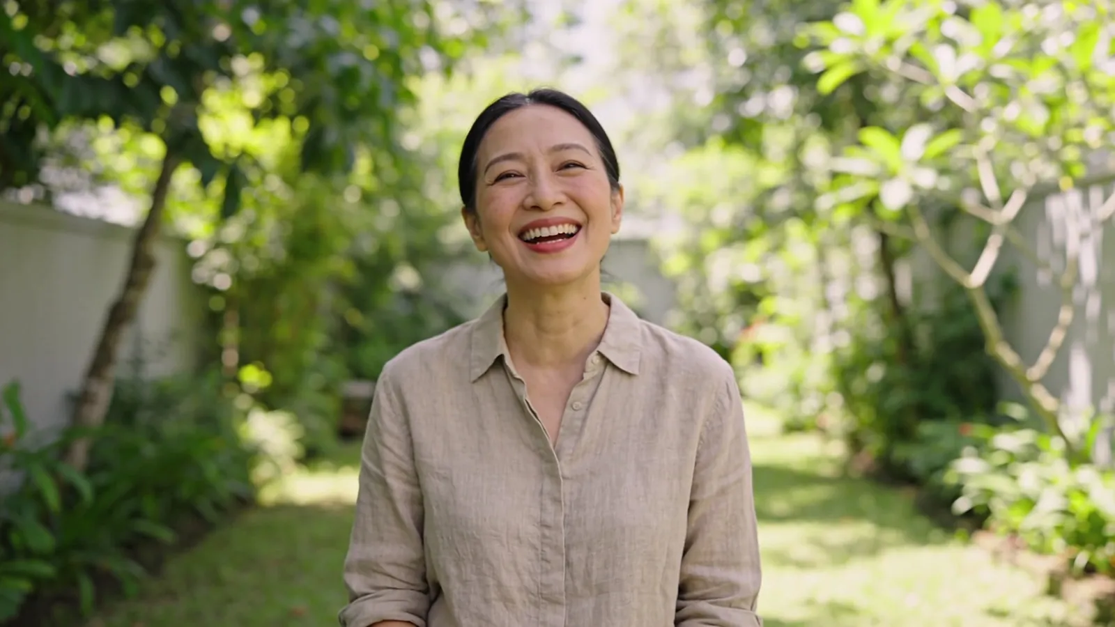 Woman in her late forties laughing naturally in a garden