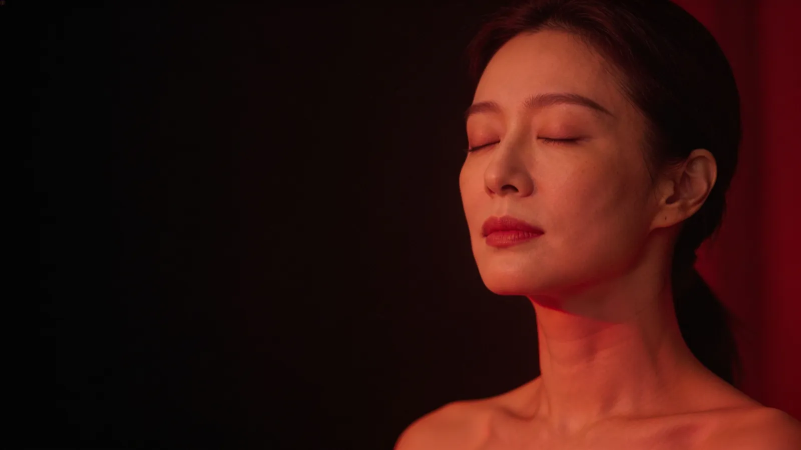 Woman with eyes closed in warm red light, illustrating red light therapy