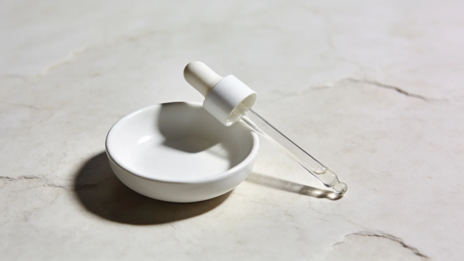Glass dropper beside a small white ceramic dish