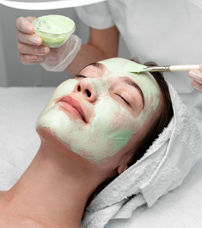 Beautician applying face mask on female client scaled